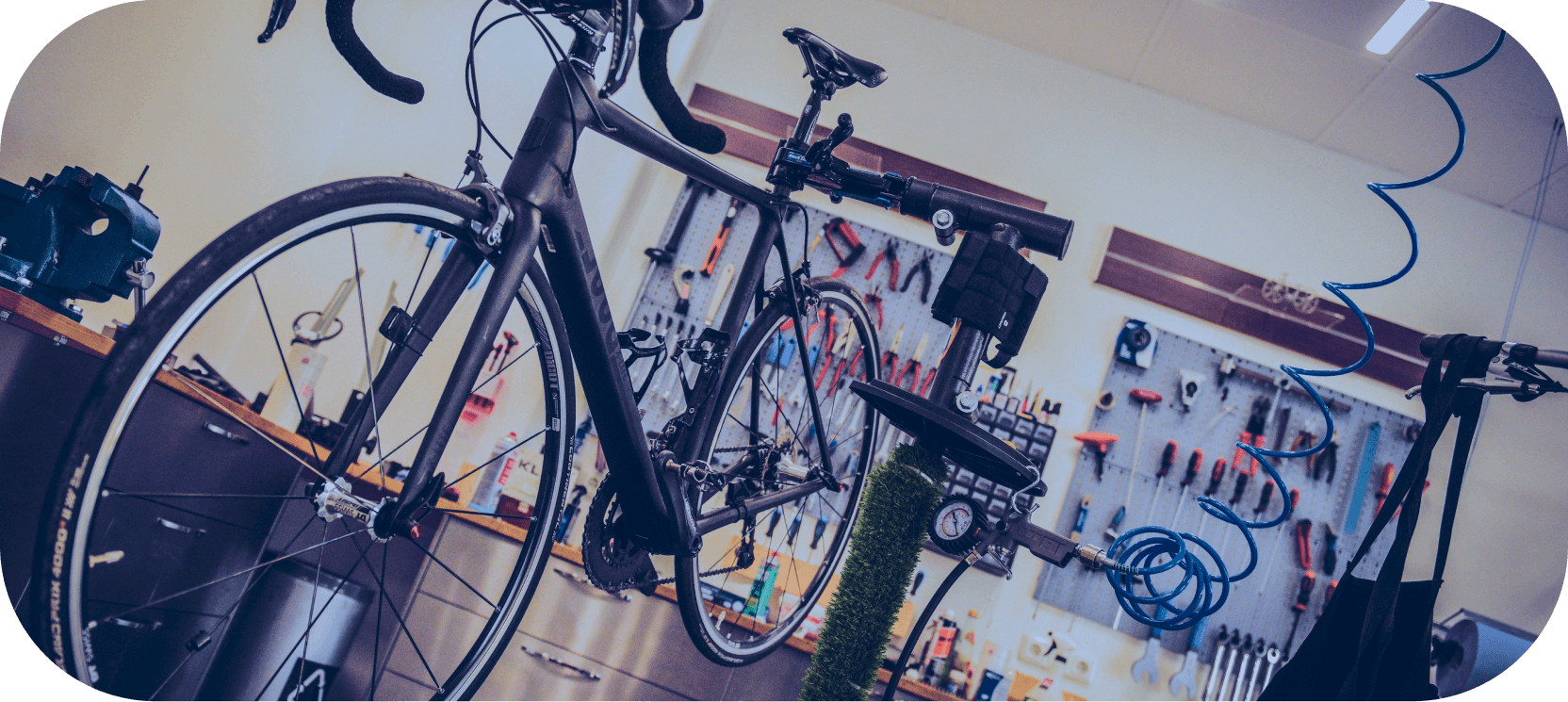 Image is taken from a bicycles repair shop. It shows a bicycle getting air pumped into its tires.